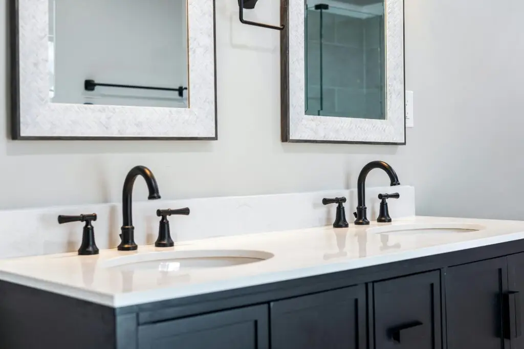 Sleek bathroom vanity featuring a double sink setup with stylish black faucets and framed mirrors.